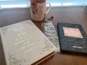 Bible journal, bookmark, 101 Prayers for Military Wives, and mug with Bible verse on table
